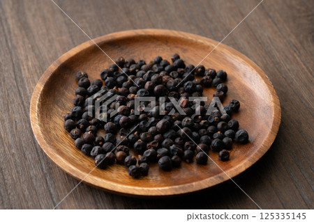 Juniper berries on a wooden plate Juniper berries on a wooden plate 125335145