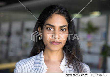 Indian businesslady looking at camera standing alone in workspace Indian businesslady looking at camera standing alone in workspace 125336366