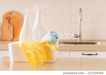 Cleaning supplies in kitchen with yellow gloves and spray bottle on counter Cleaning supplies in kitchen with yellow gloves and spray bottle on counter 125336406