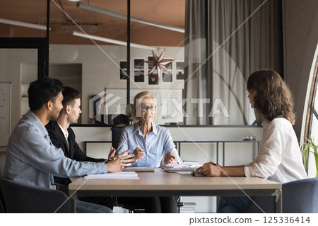Mid-aged business woman speaking at international team meeting Mid-aged business woman speaking at international team meeting 125336414