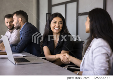 Two multiethnic businesswomen greeting each other with handshake gesture 125336542