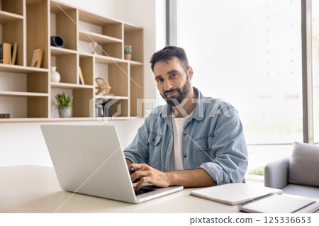 Portrait happy young man freelancer sitting at desk by notebook 125336653