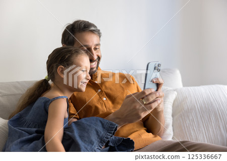 Preteen daughter spend leisure time with loving dad using smartphone 125336667