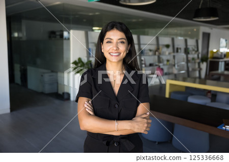 Attractive businesswoman posing in office with her arms-crossed 125336668