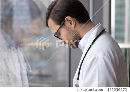 Tired sad stressed young male doctor standing with closed eyes 125336673