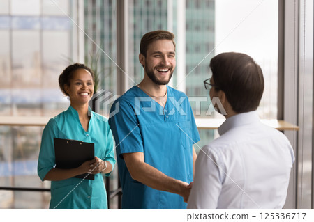 Happy young male doctor shake hand of businessman at clinic Happy young male doctor shake hand of businessman at clinic 125336717