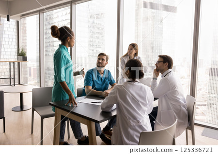 Diverse medical team multiethnic doctors gather at table for discussion 125336721