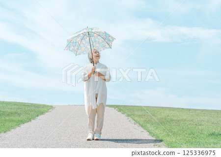 打著陽傘在公園散步的老年婦女 125336975