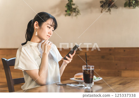 亞洲女性正在用智能手機查看前來吃午餐的咖啡館和餐館的評論和 SNS 亞洲女性正在用智能手機查看前來吃午餐的咖啡館和餐館的評論和 SNS 125337338