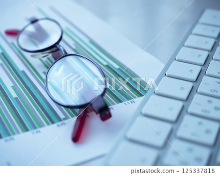 Graph, keyboard and glasses on a table 125337818
