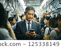 一位商人乘坐擁擠的火車，看著他的智慧型手機 125338149