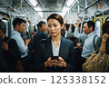一位年輕女子乘坐擁擠的火車，看著她的智慧型手機 125338152