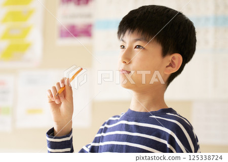 小學生手裡拿著鉛筆思考 125338724