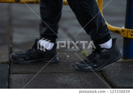 Individuals are engaged in running activity on pavement bright athletic shoes. Early morning light creates fresh atmosphere for fitness enthusiasts. Individuals are engaged in running activity on pavement bright athletic shoes. Early morning light creates fresh atmosphere for fitness enthusiasts. 125338839