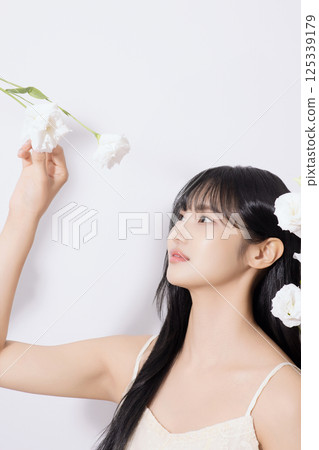 Portrait of young woman looking at white flowers 125339179