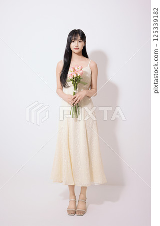 Portrait of young woman holding white flower Portrait of young woman holding white flower 125339182