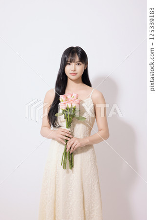 Cropped view of young woman wearing white dress and holding tulips 125339183