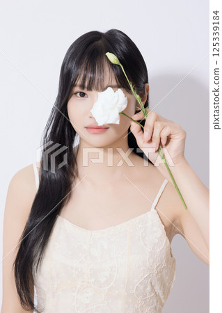 Portrait of young woman holding white flower 125339184