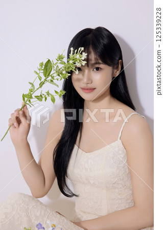Portrait of a young woman sitting and holding flowers Portrait of a young woman sitting and holding flowers 125339228