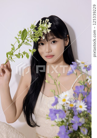Portrait of a young woman sitting and holding flowers 125339229
