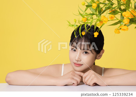 Portrait of a young woman lying face down in front of a table with a vase on it 125339234