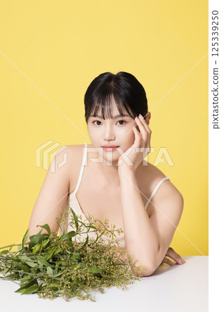 Portrait of a young woman sitting in front of a pile of leaves 125339250