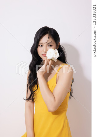 Portrait of young woman wearing yellow dress and holding bouquet of flowers 125339321