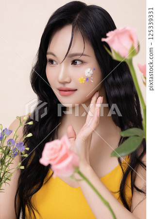 Portrait of a beautiful woman with face paint on her face and surrounded by flowers 125339331