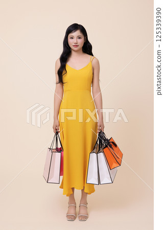 A woman in her 20s holding shopping bags in both hands 125339390