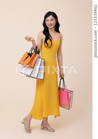 A woman in her 20s holding shopping bags in both hands 125339402