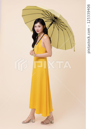 A woman in her 20s wearing a yellow umbrella 125339406