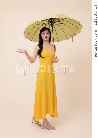 A woman in her 20s wearing a yellow umbrella 125339413