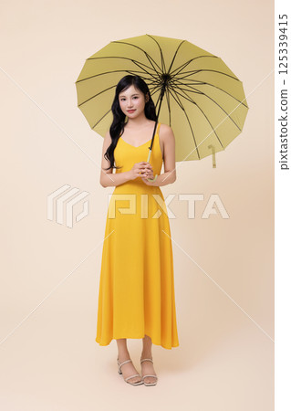 A woman in her 20s wearing a yellow umbrella 125339415