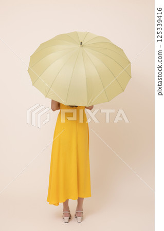 A woman in her 20s wearing a yellow umbrella 125339416