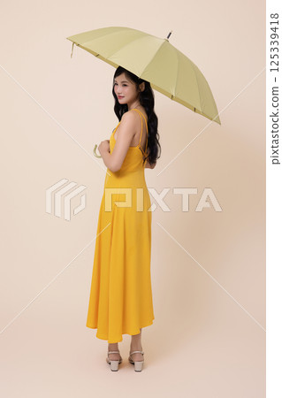 A woman in her 20s wearing a yellow umbrella 125339418