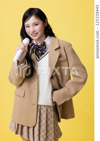 A girl wearing a school uniform and singing with a microphone A girl wearing a school uniform and singing with a microphone 125339445