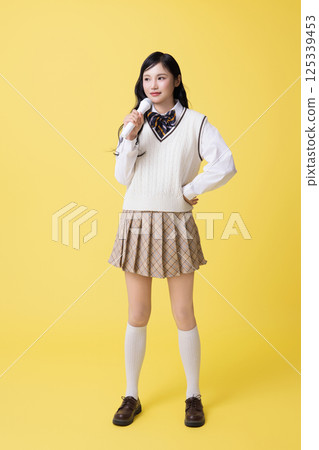 A girl wearing a school uniform and singing with a microphone A girl wearing a school uniform and singing with a microphone 125339453