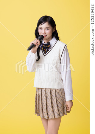 A girl wearing a school uniform and singing with a microphone A girl wearing a school uniform and singing with a microphone 125339458