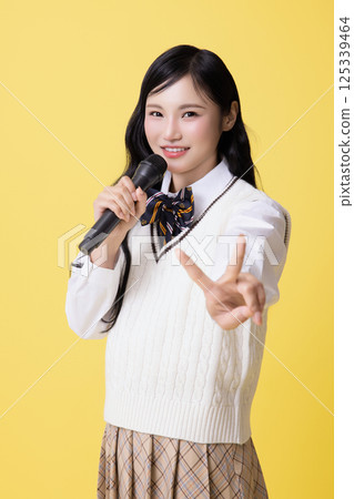 A girl wearing a school uniform and singing with a microphone 125339464