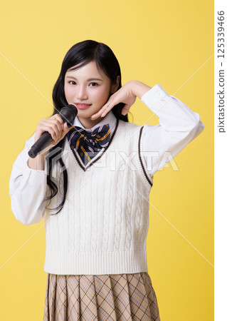 A girl wearing a stage costume and singing while holding a microphone 125339466