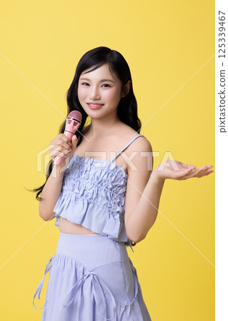 A girl wearing a stage costume and singing while holding a microphone 125339467
