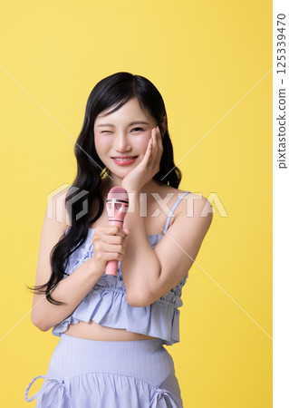 A girl wearing a stage costume and singing while holding a microphone 125339470