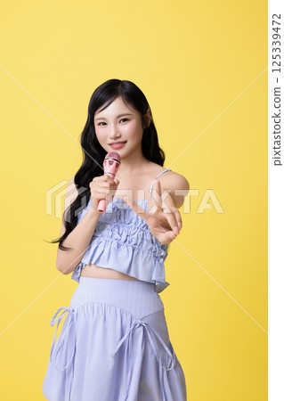 A girl wearing a stage costume and singing while holding a microphone 125339472