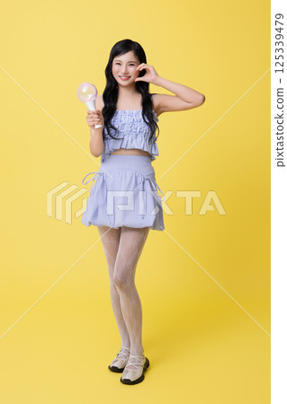 A girl wearing a stage costume and posing with a light stick A girl wearing a stage costume and posing with a light stick 125339479