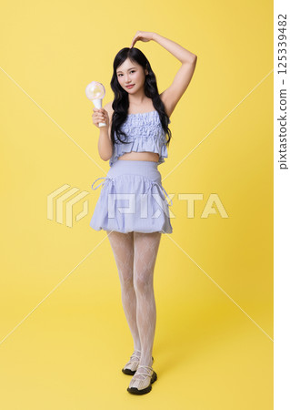 A girl wearing a stage costume and posing with a light stick A girl wearing a stage costume and posing with a light stick 125339482