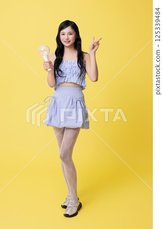 A girl wearing a stage costume and posing with a light stick 125339484