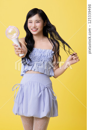 A girl wearing a stage costume and posing with a light stick 125339498