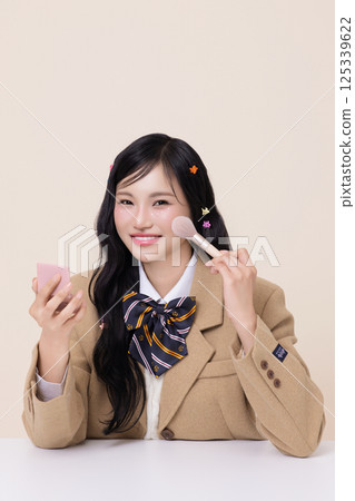 Portrait of a pretty girl wearing a school uniform and posing with cosmetics 125339622