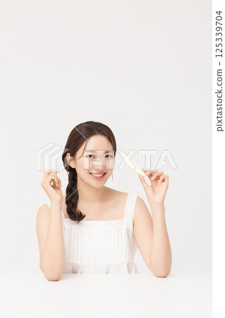 Cropped view of young woman posing with lip balm 125339704