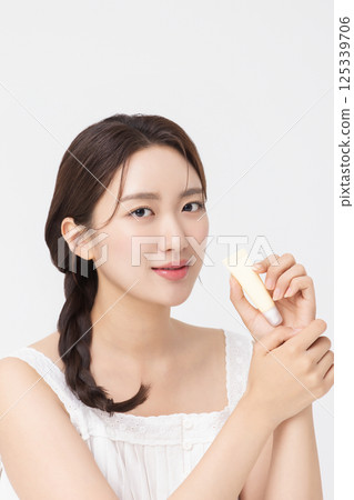 Cropped view of young woman posing with lip balm 125339706